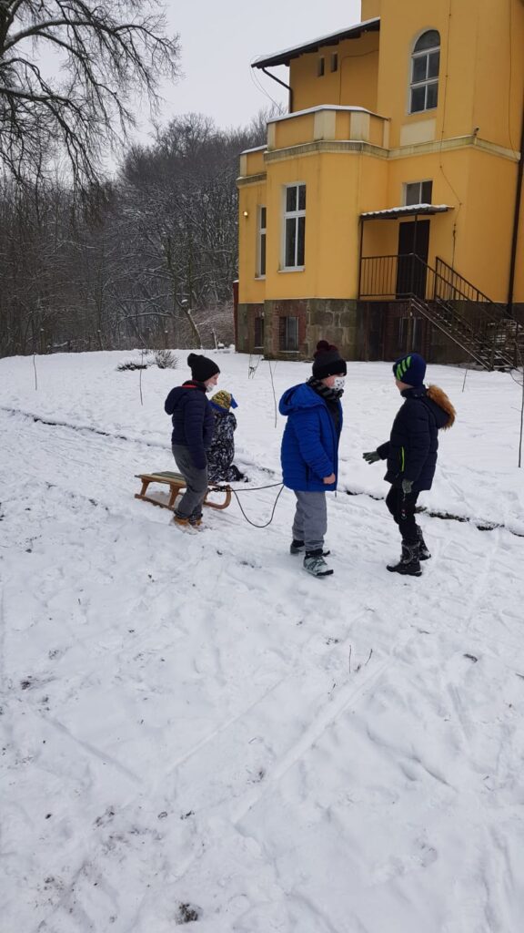 Dzieci stoją przy sankach